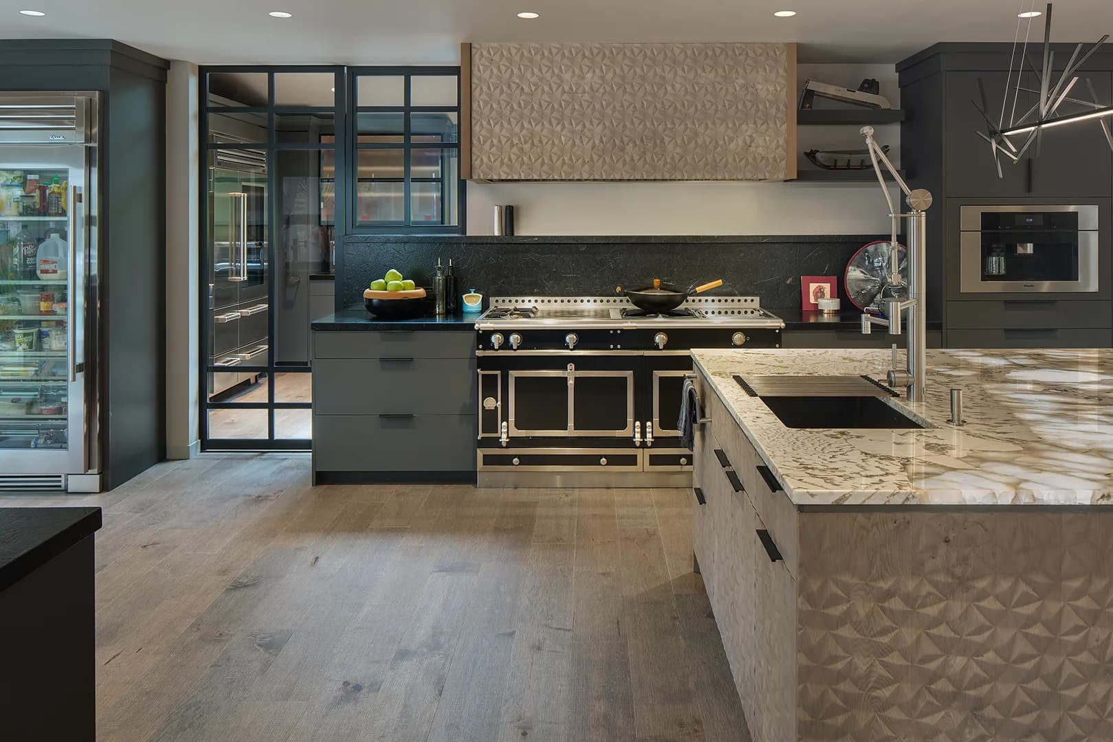 Contemporary Studio Stratton kitchen with a professional range, charcoal cabinetry, and a sculpted stone island
