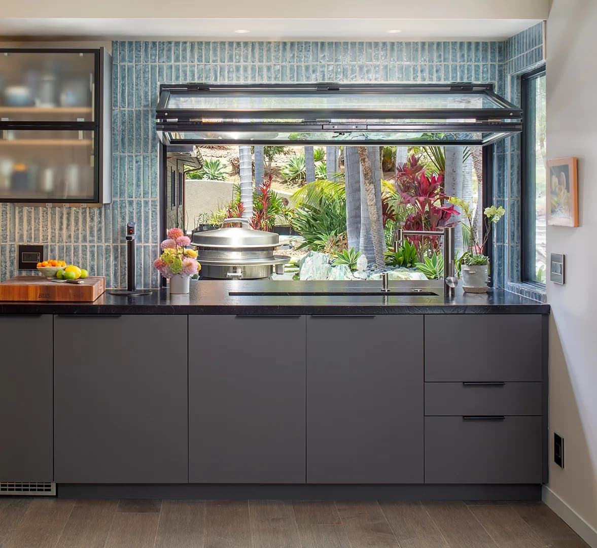 Blue tile Studio Stratton scullery with a pass-through window, detailed cabinetry, and a garden view